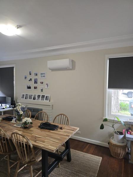 Wall-mounted split system air conditioner above a dining table in a family home