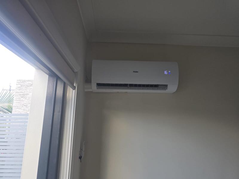 Split system air conditioner mounted beside a sliding door in a bright family room