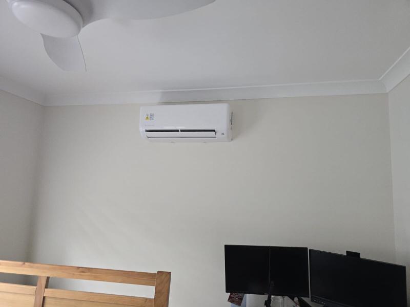 Split system air conditioner installed high on the wall of a home office with a ceiling fan