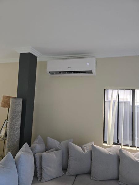 Split system head unit mounted high on a living room wall above a cushioned lounge
