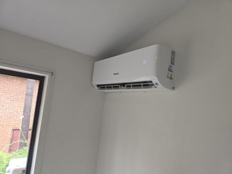 New split system head unit on the wall of an open-plan living area beside a doorway