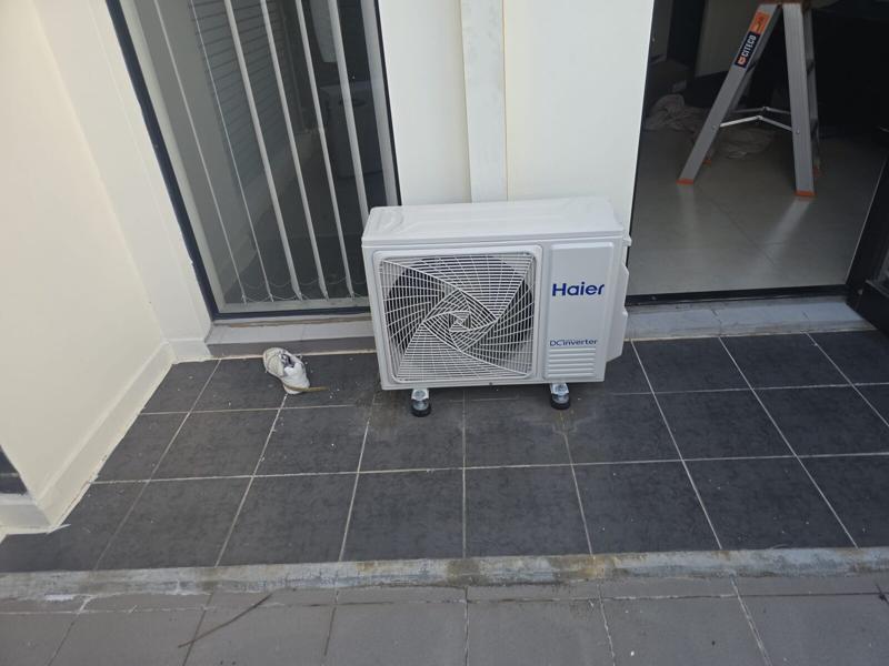 Outdoor air conditioning unit standing on levelled feet in a tiled courtyard