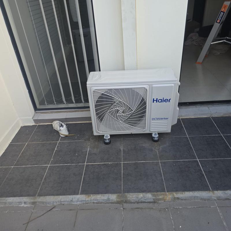 Outdoor air conditioning unit standing on levelled feet in a tiled courtyard
